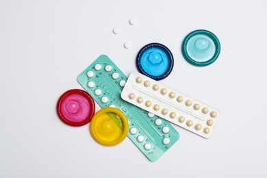 Condoms and birth control pills on light grey background, flat lay. Safe sex concept