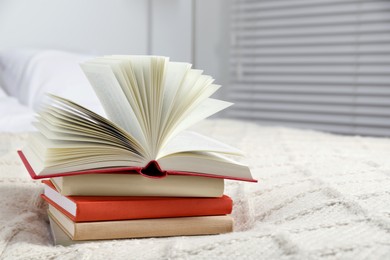 Photo of Books on white soft blanket in bedroom, space for text