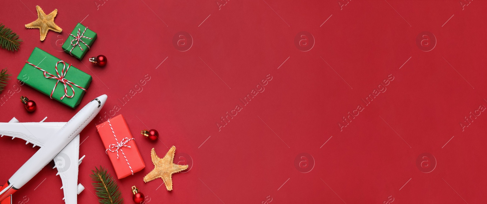 Image of Flat lay composition with toy airplane, gift boxes and space for text on red background. Christmas vacation