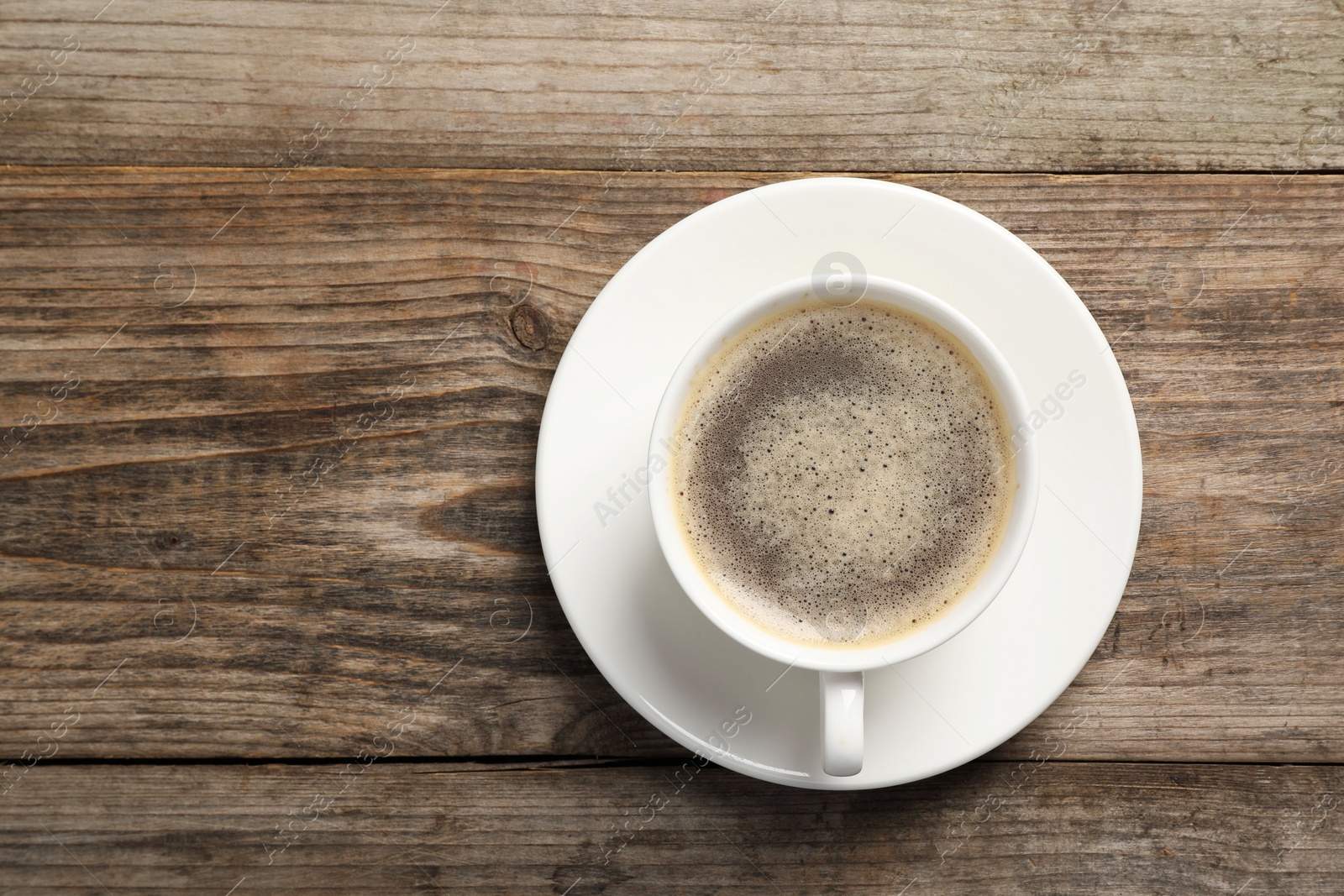 Photo of Tasty coffee in cup on wooden table, top view. Space for text