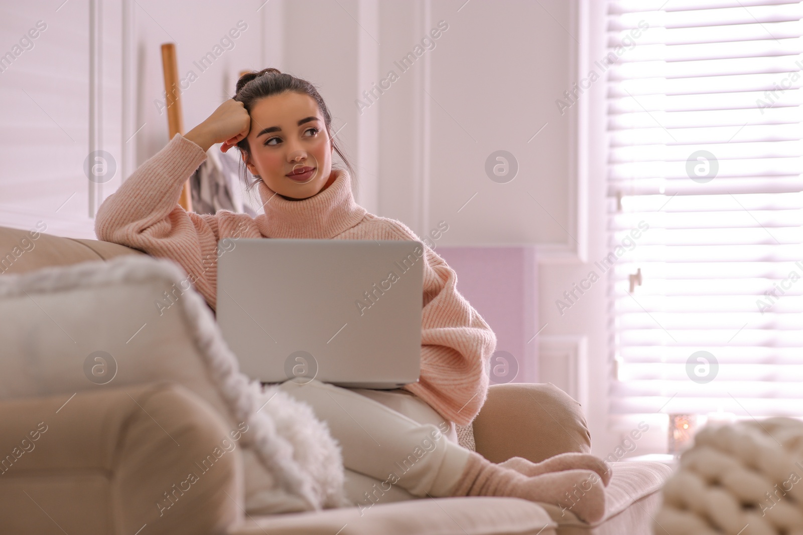 Photo of Beautiful young woman with laptop relaxing at home. Cozy atmosphere