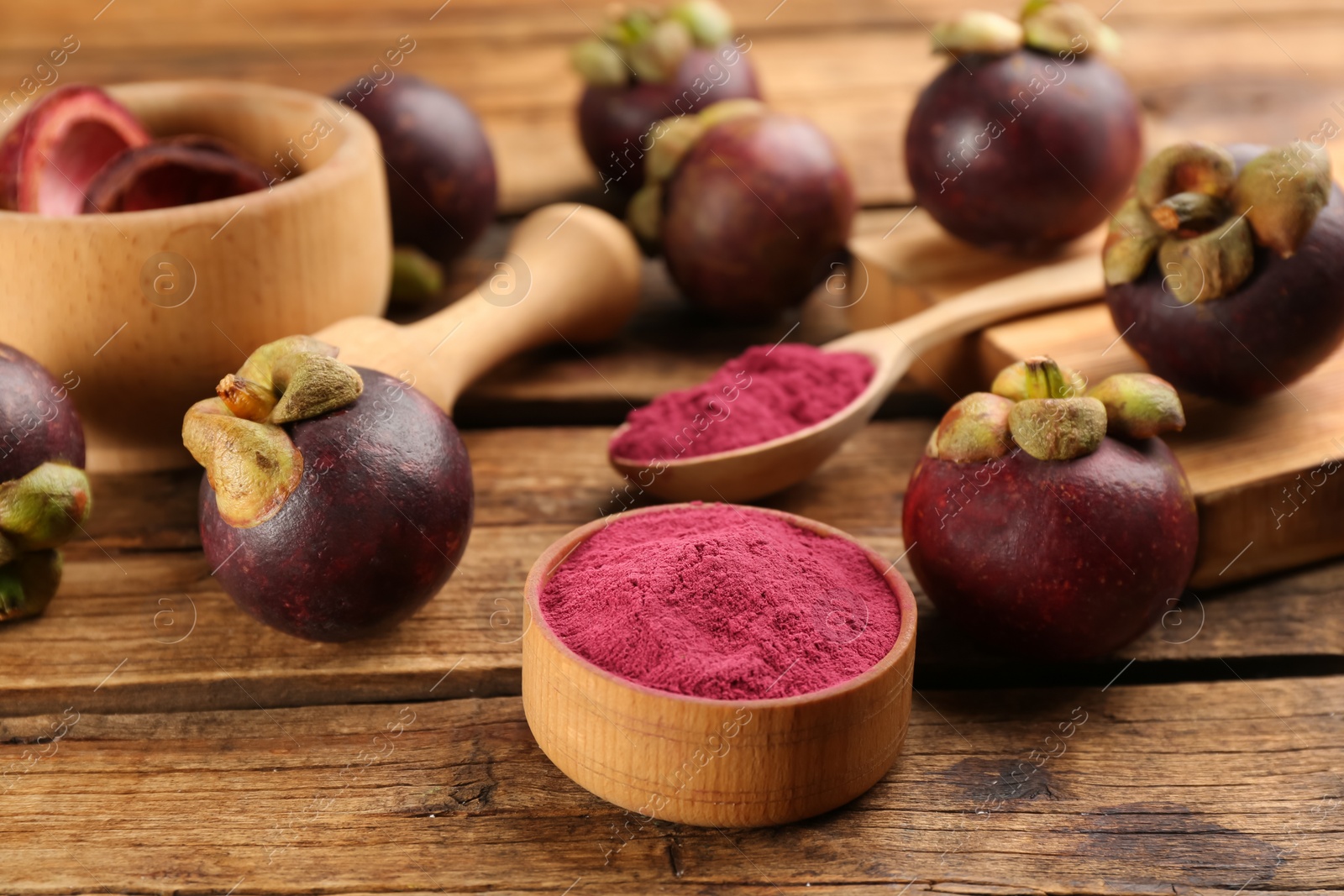 Photo of Purple mangosteen powder and fruits on wooden table