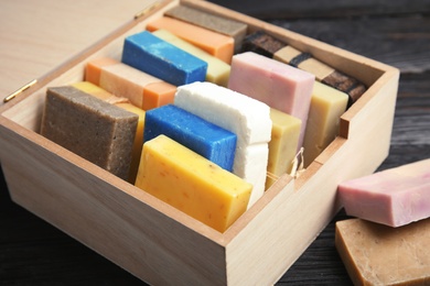 Many different handmade soap bars in wooden box on table, closeup