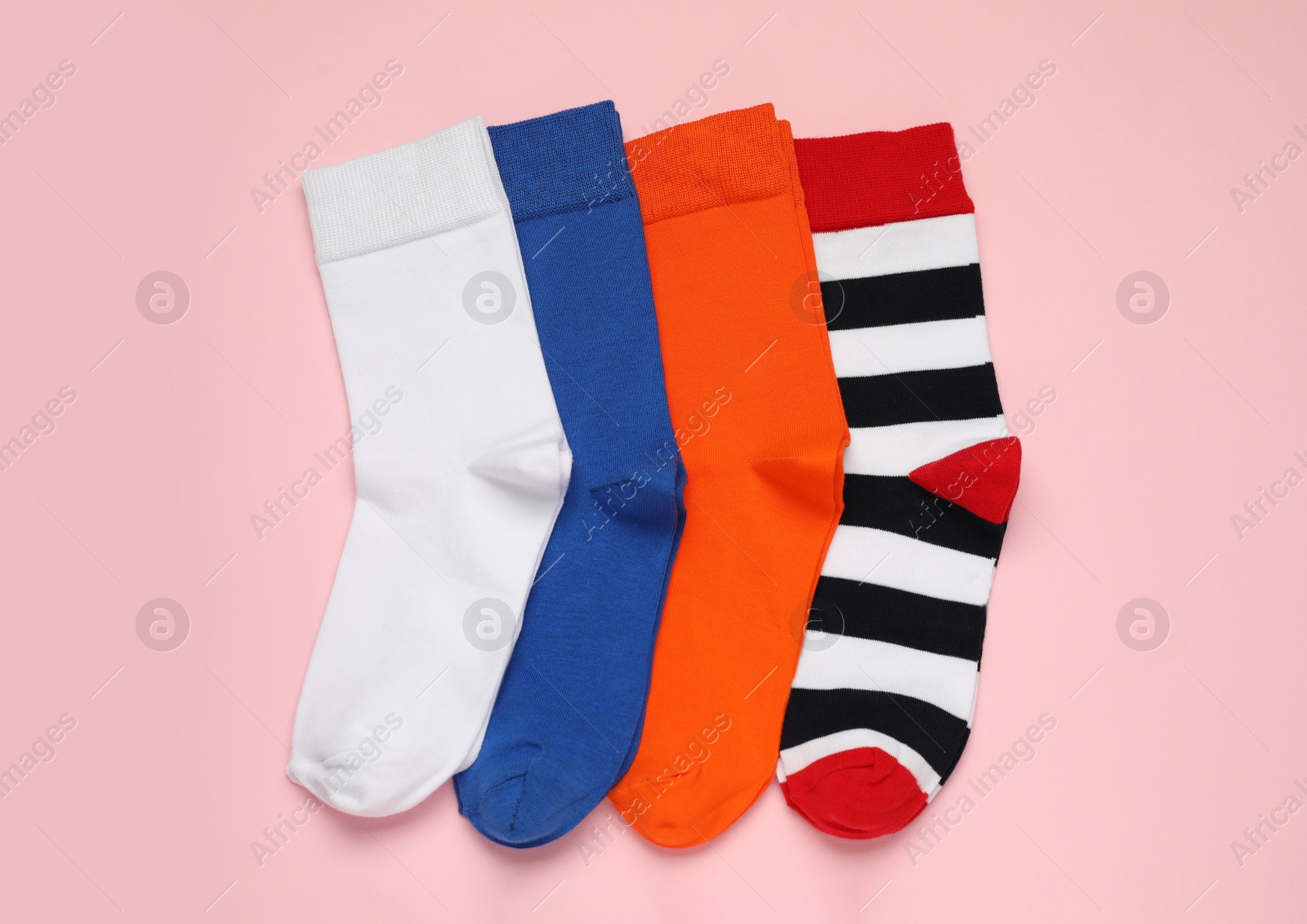 Photo of Different colorful socks on pink background, flat lay