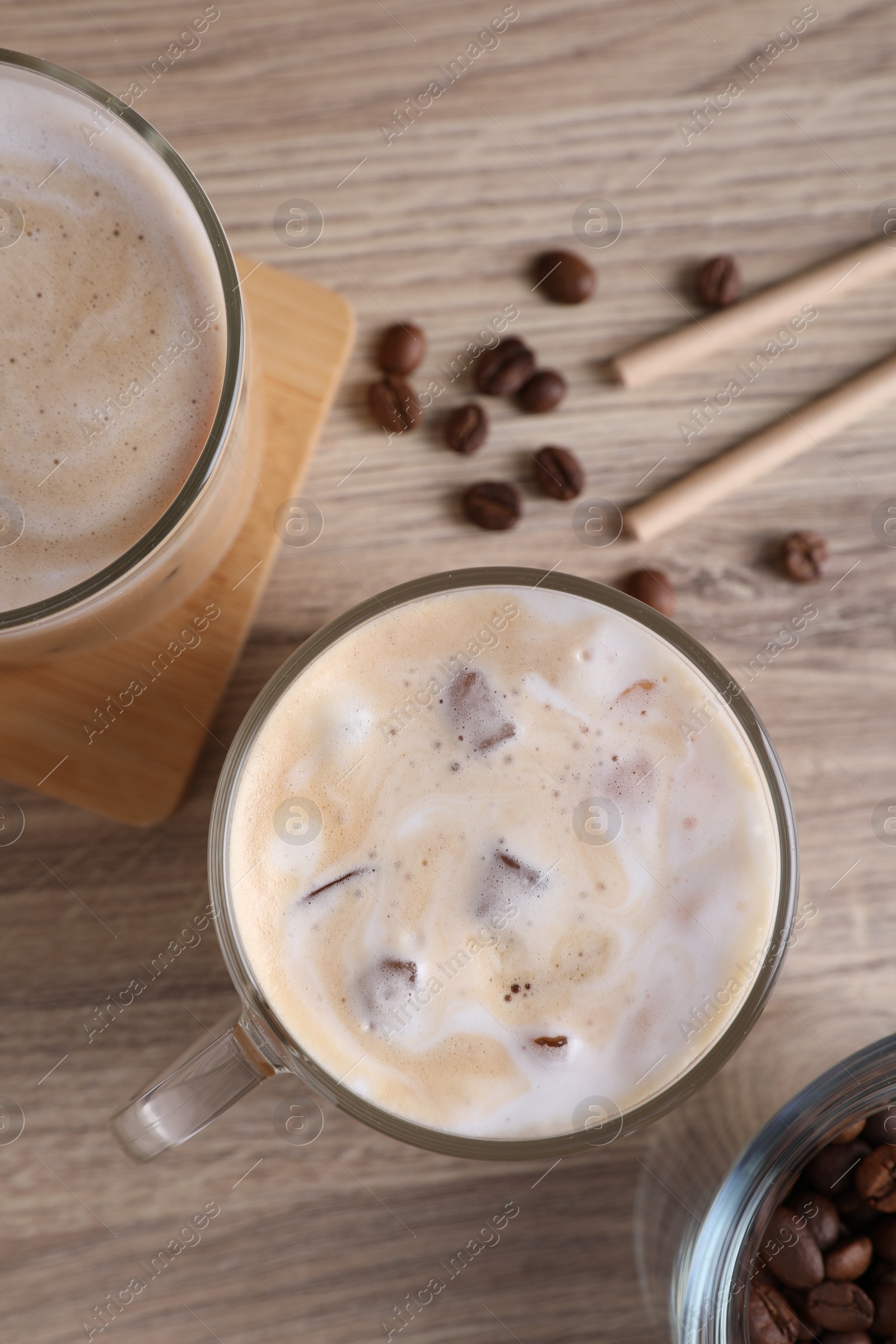 Photo of Fresh iced coffee and beans on wooden table, flat lay