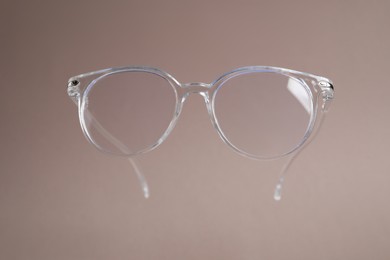 Stylish pair of glasses on pale brown background