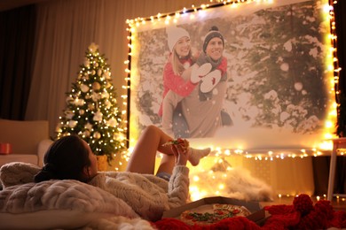 Image of Woman watching romantic movie via video projector in room. Cozy winter holidays atmosphere