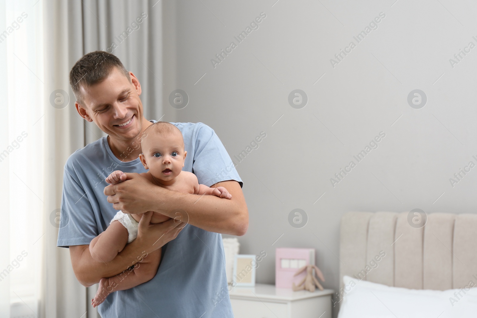 Photo of Happy father holding his cute baby at home, space for text