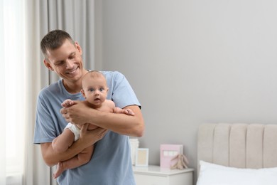 Happy father holding his cute baby at home, space for text