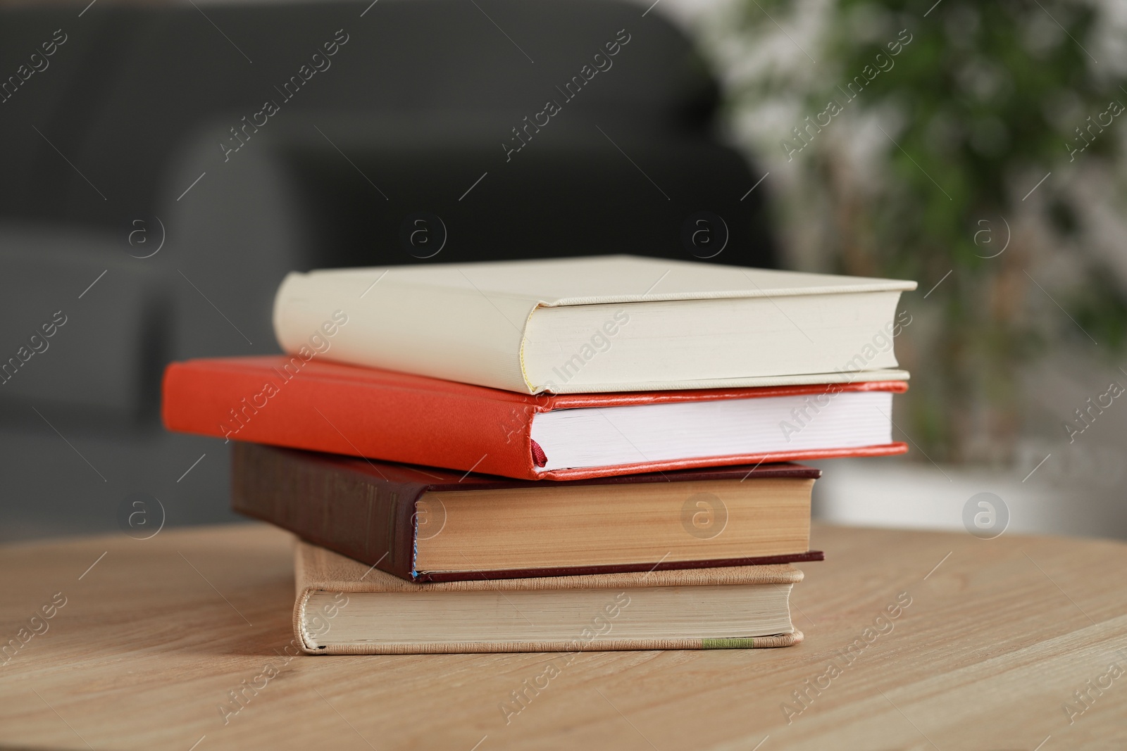 Photo of Stack of different hardcover books on wooden table indoors