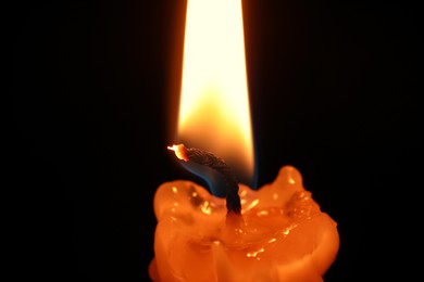 Photo of Burning candle on black background, closeup view