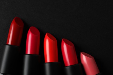Photo of Beautiful lipsticks on black background, flat lay. Space for text