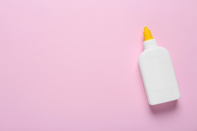 Photo of Bottle of glue on pink background, top view. Space for text