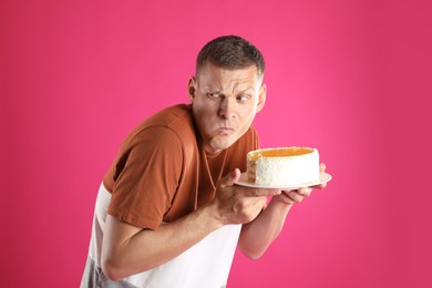 Greedy man eating tasty cake on pink background