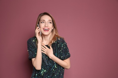 Young woman talking on phone against color background