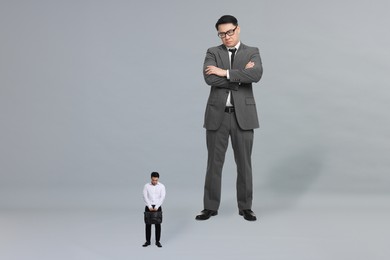 Giant boss and sad small man on grey background