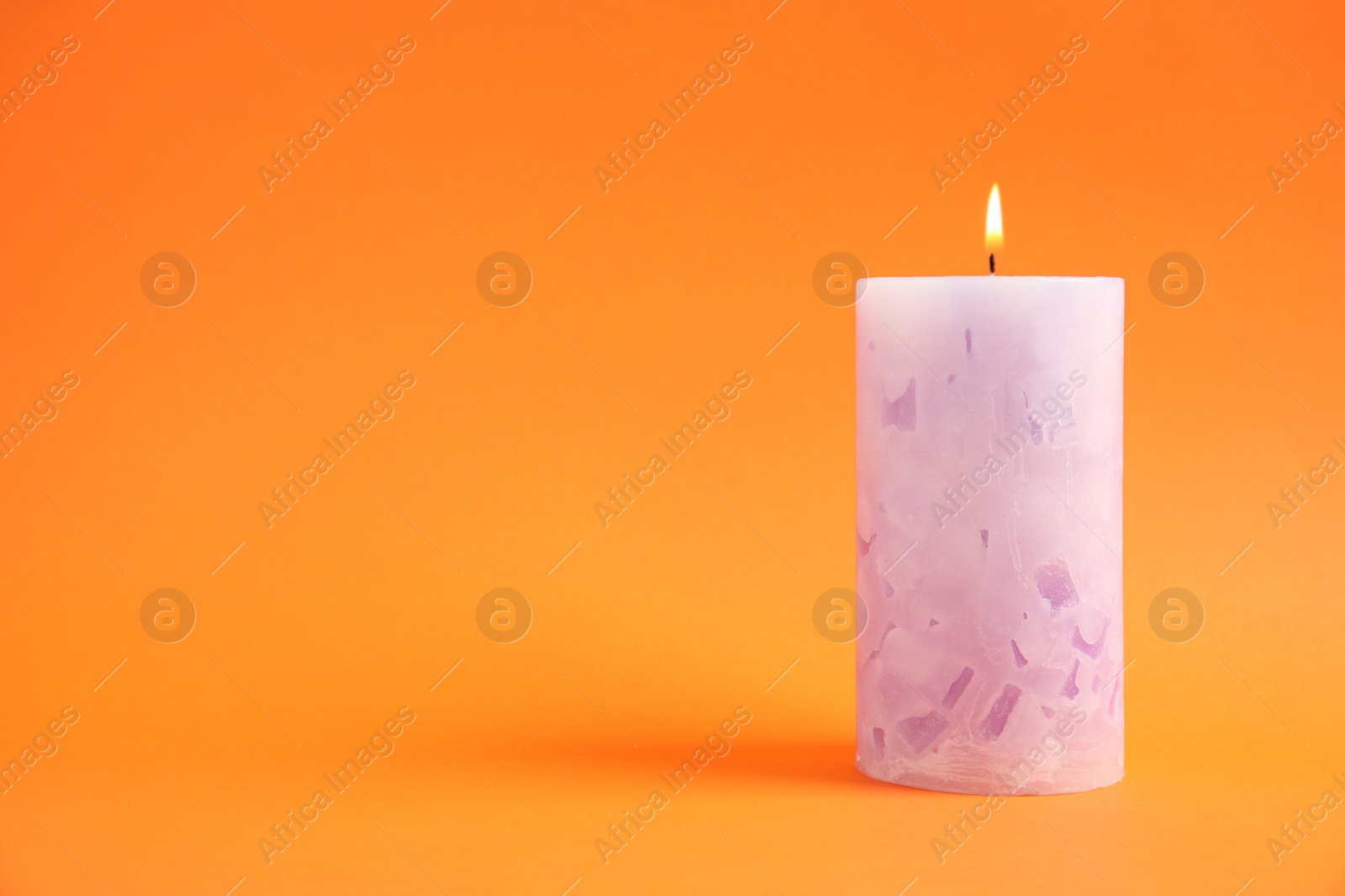 Photo of Alight wax candle on color background. Space for text