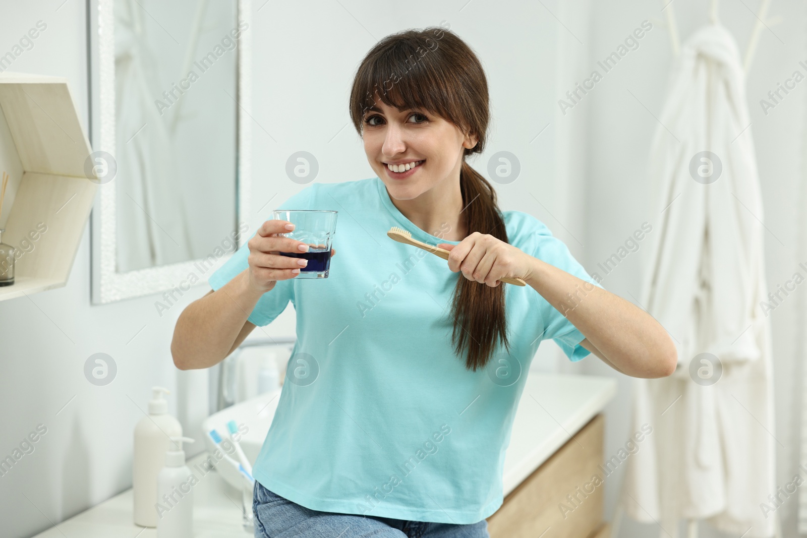 Photo of Young woman with mouthwash and toothbrush in bathroom