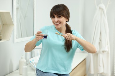 Photo of Young woman with mouthwash and toothbrush in bathroom