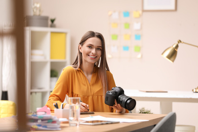 Photo of Young journalist with camera at table in office