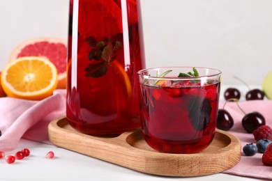 Delicious refreshing sangria, fruits and berries on white table, closeup