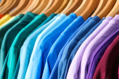 Hangers with bright clothes as background, closeup