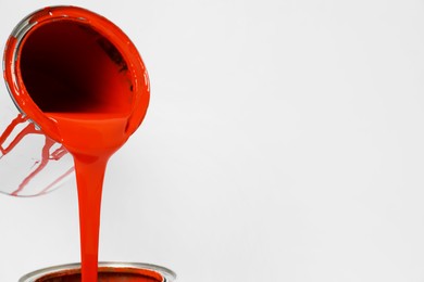 Photo of Pouring orange paint from can on white background, closeup. Space for text