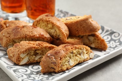 Photo of Tray with tasty cantucci and glasses of liqueur on light table, closeup. Traditional Italian almond biscuits