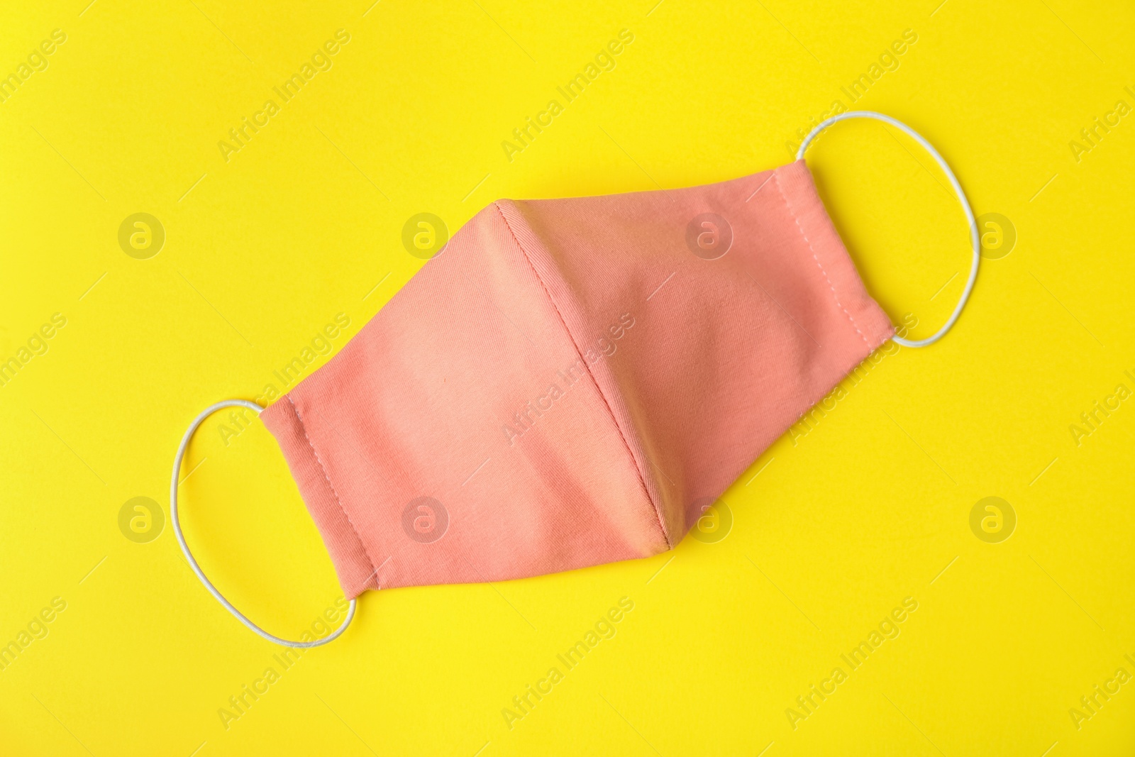 Photo of Homemade protective face mask on yellow background, top view