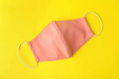 Photo of Homemade protective face mask on yellow background, top view