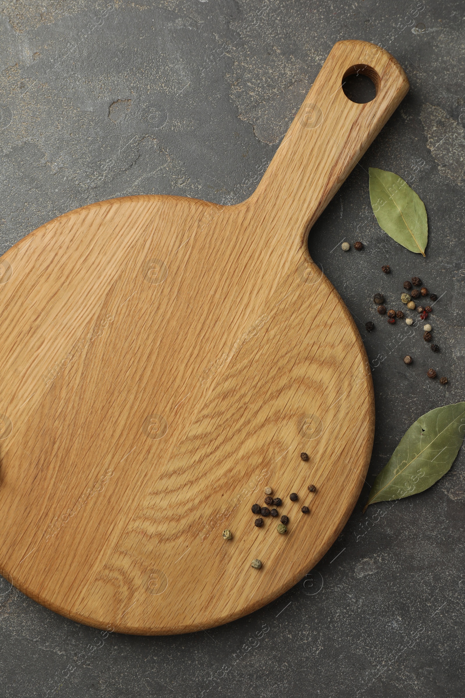 Photo of Cutting board, pepper and bay leaves on grey table, flat lay. Space for text