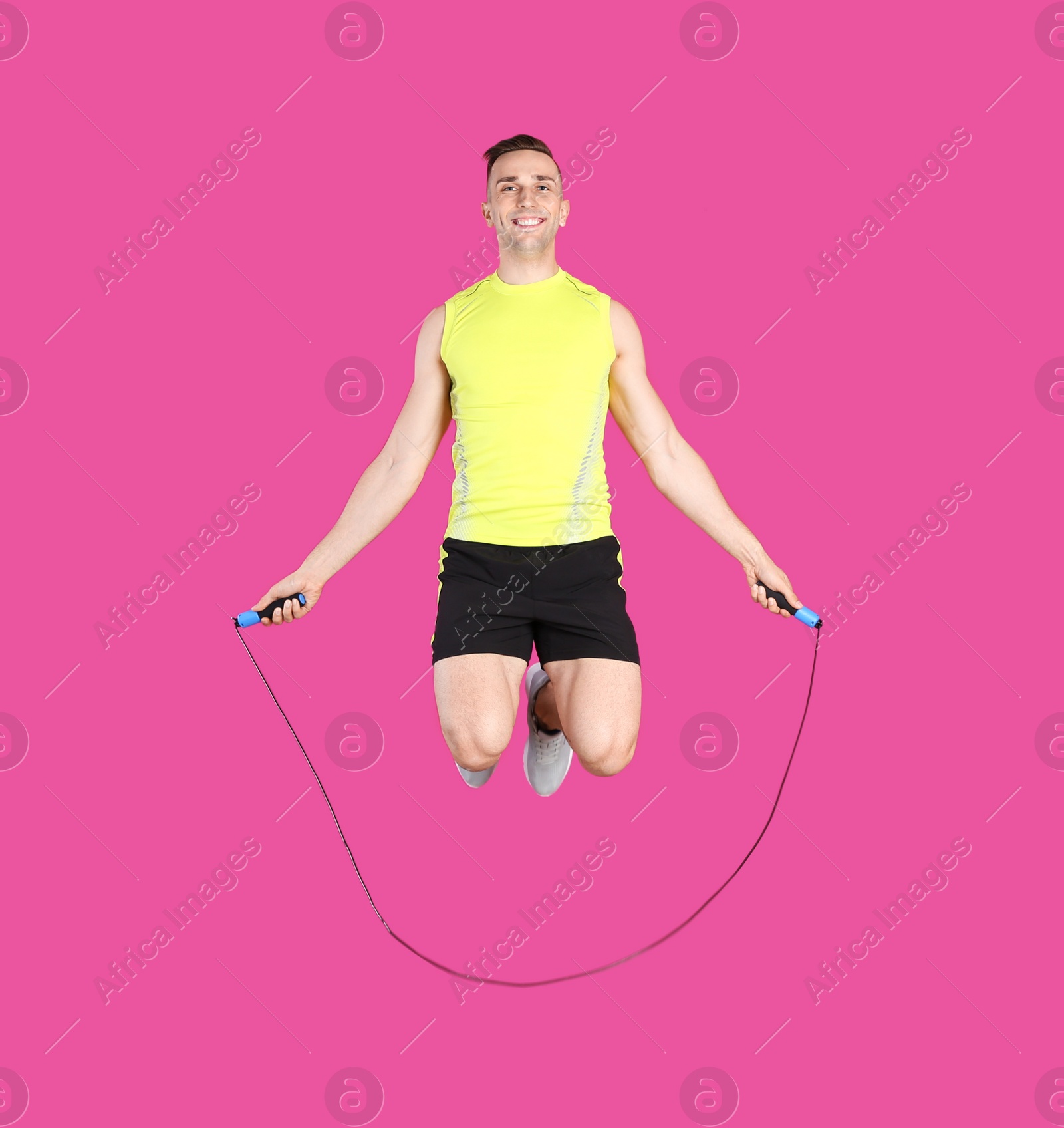 Photo of Full length portrait of young sportive man training with jump rope on color background