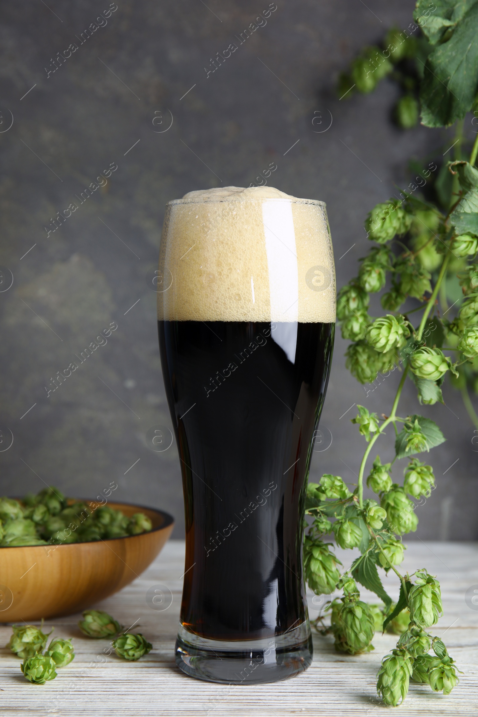 Photo of Composition with tasty beer and fresh green hops on wooden table