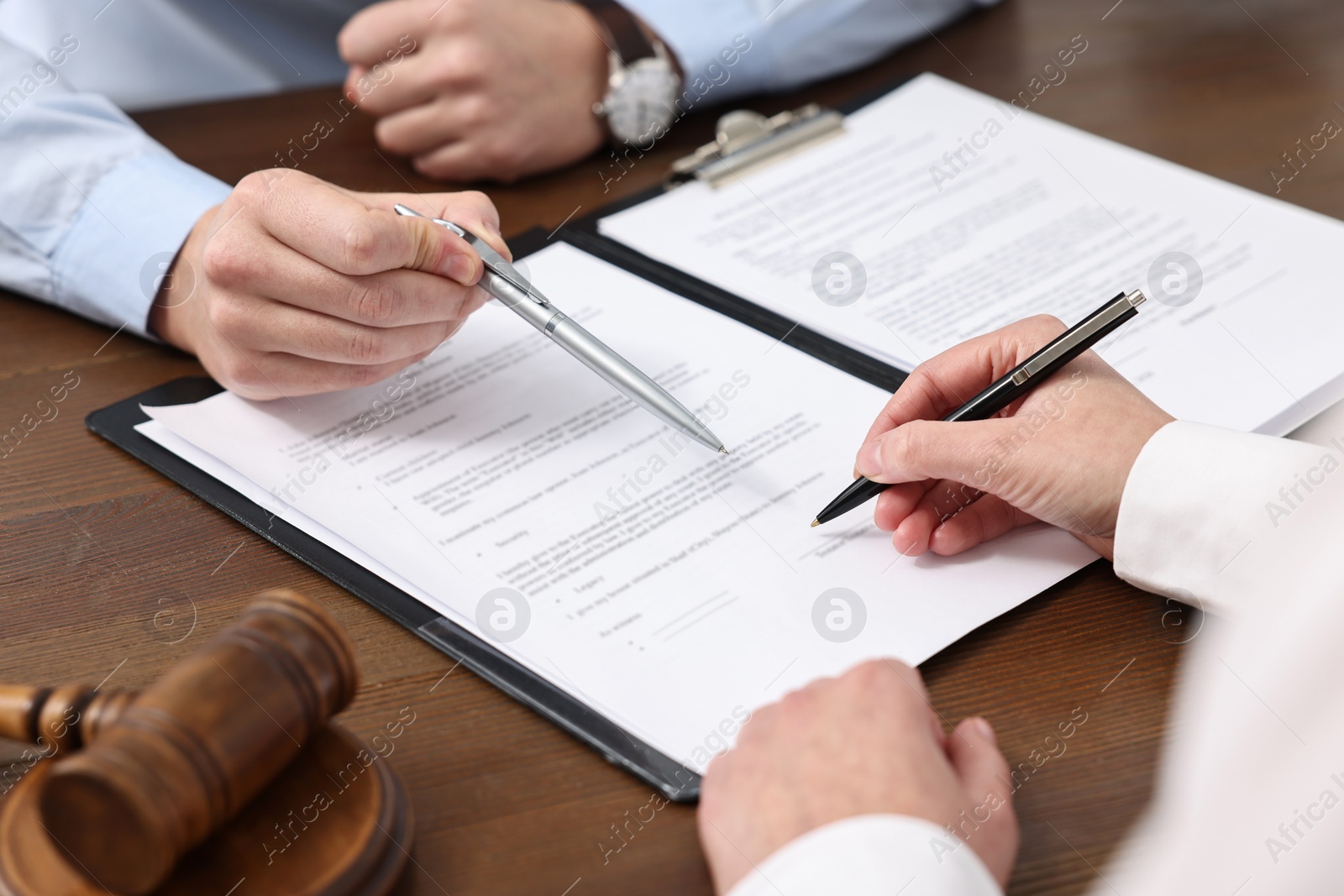 Photo of Lawyers working with documents at wooden table, closeup