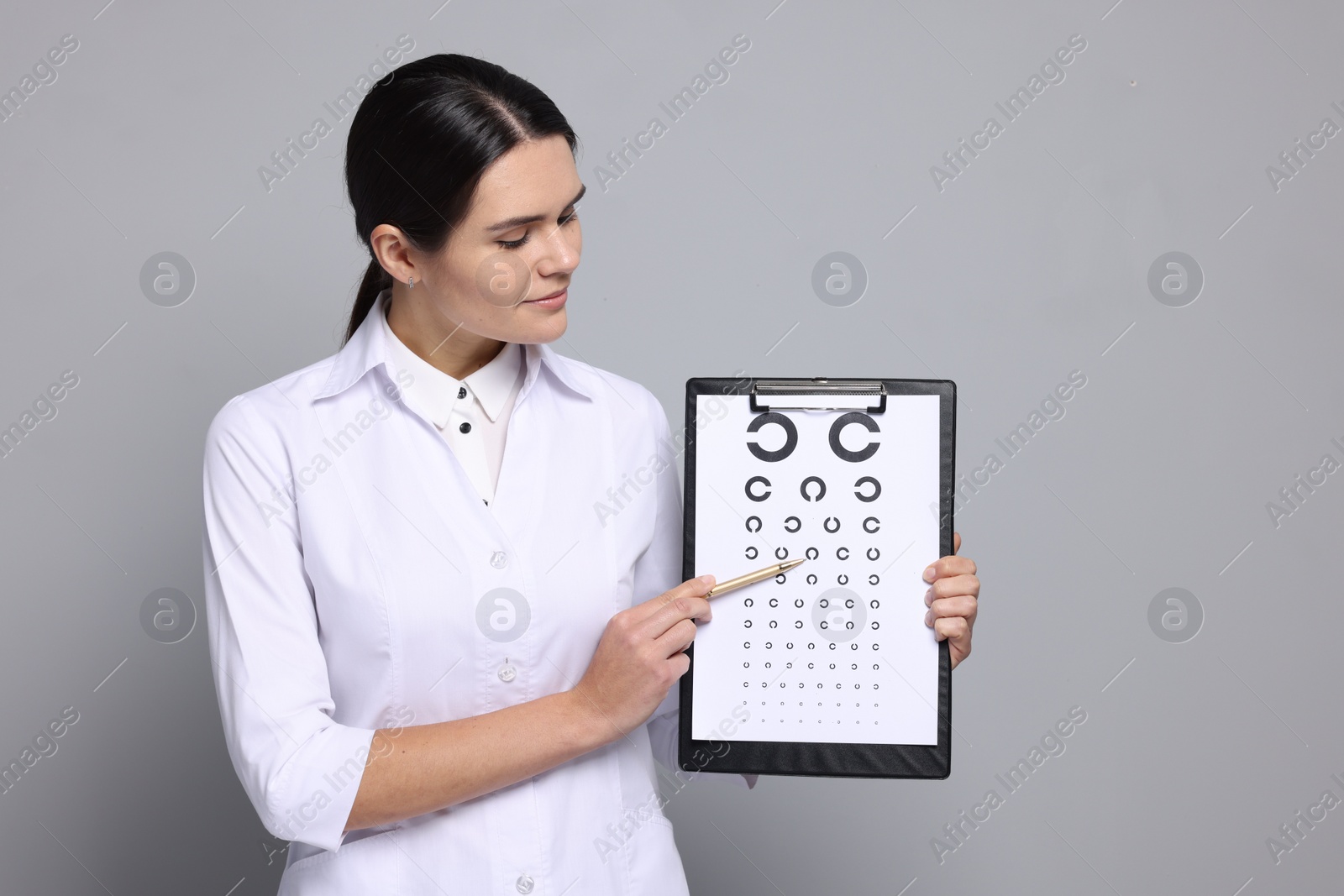 Photo of Ophthalmologist pointing at vision test chart on gray background