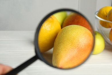 Photo of View through magnifying glass on pears, closeup. Poison detection
