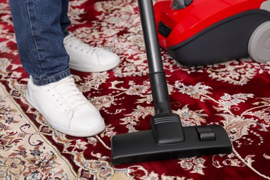 Man cleaning carpet with vacuum cleaner at home, closeup