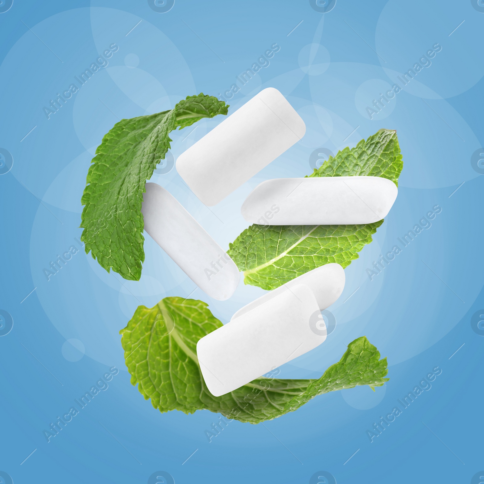 Image of Fresh mint leaves and chewing gum pads falling on blue background