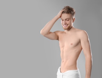 Photo of Portrait of young man with slim body in towel on grey background. Space for text
