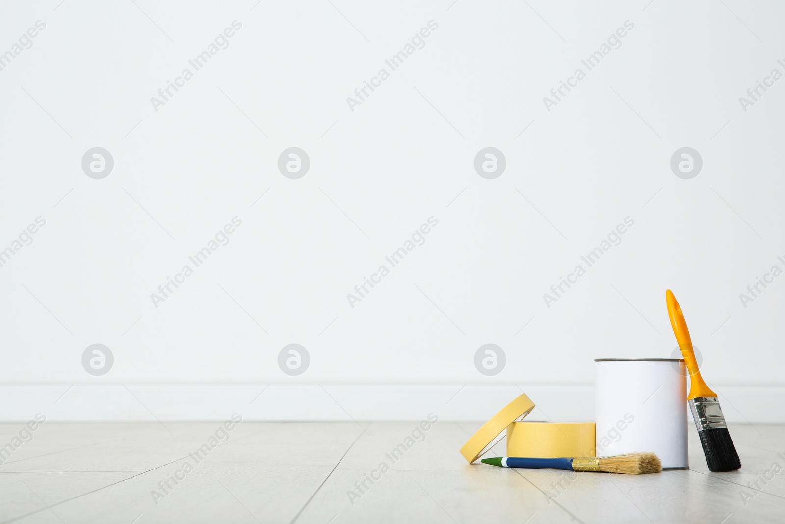 Photo of Can of paint and decorator tools on wooden floor indoors. Space for text