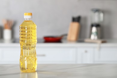 Photo of Bottle of cooking oil on white marble table in kitchen. Space for text