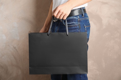 Photo of Man holding mock-up of paper shopping bag on color background