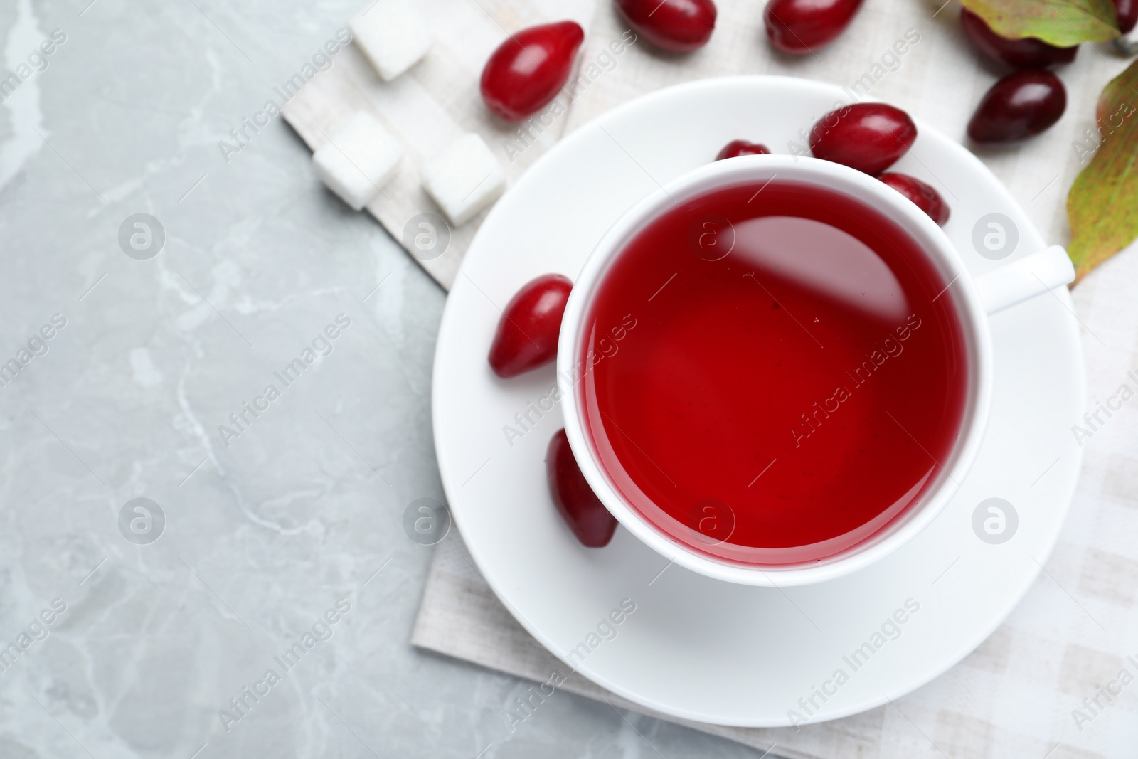 Photo of Cup of fresh dogwood tea and berries on light grey table, flat lay. Space for text