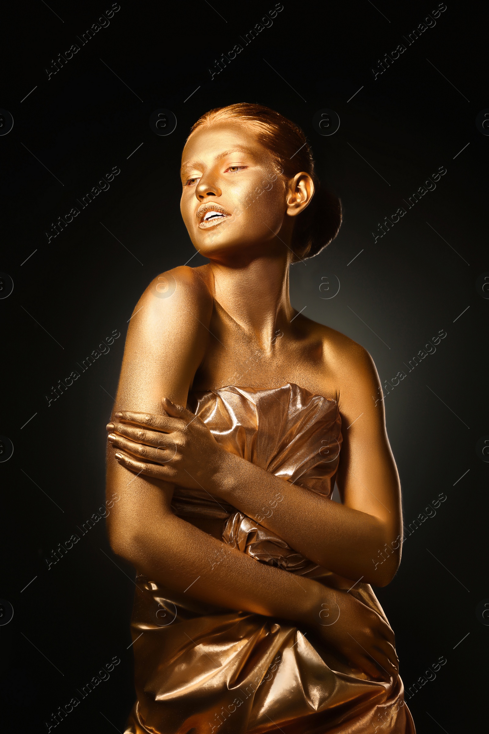 Photo of Portrait of beautiful lady with gold paint on skin against black background