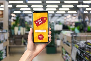 Woman holding smartphone with activated promo code in gardening store, closeup