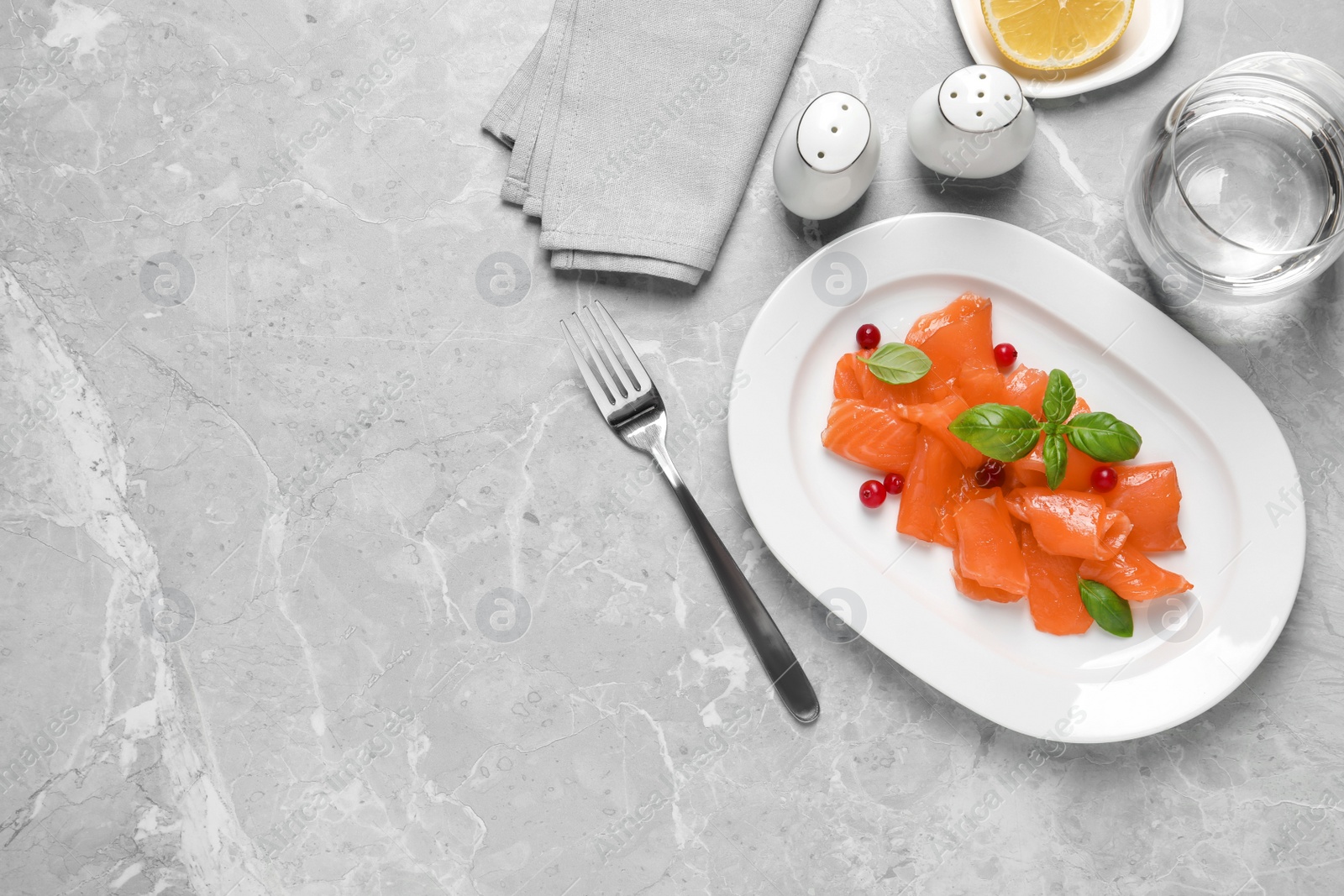 Photo of Salmon carpaccio with cranberries and basil served on grey table, flat lay. Space for text