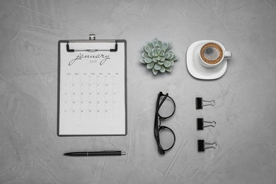 Photo of Flat lay composition with calendar and cup of coffee on grey table