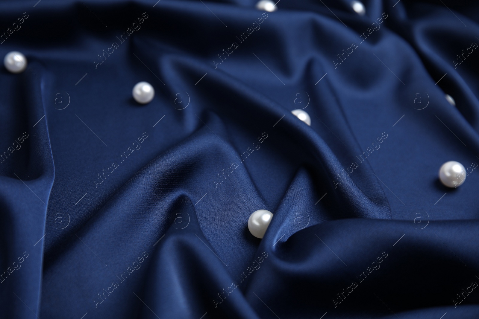 Photo of Many beautiful pearls on delicate dark blue silk, closeup