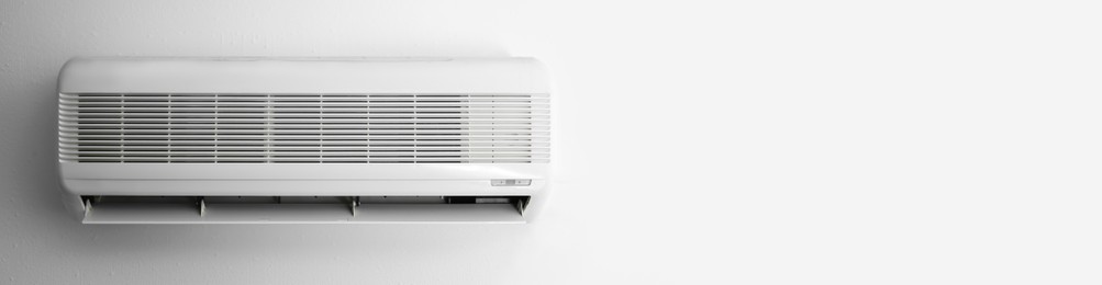 Image of Modern air conditioner on white wall indoors, space for text. Banner design