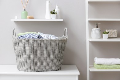 Photo of Wicker basket with dirty laundry on table indoors